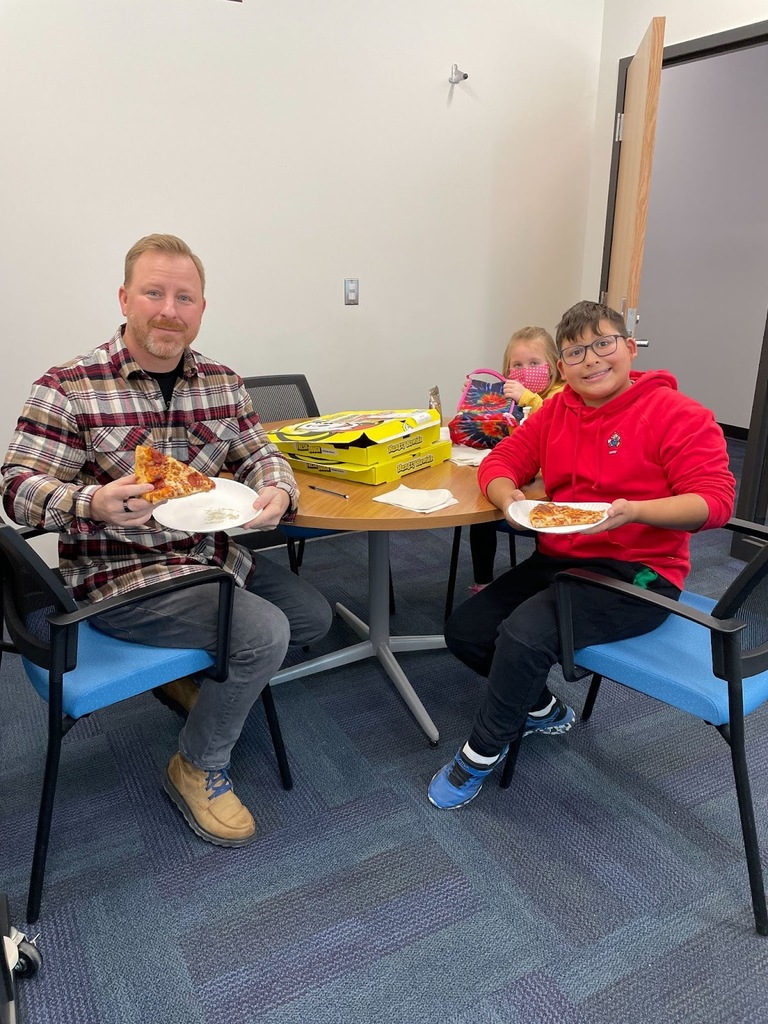 two students and principal eating pizza at a table