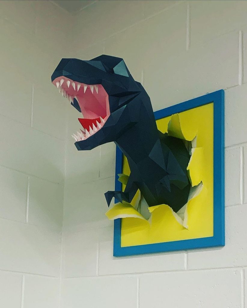 Paper t-rex bust attached to wall.