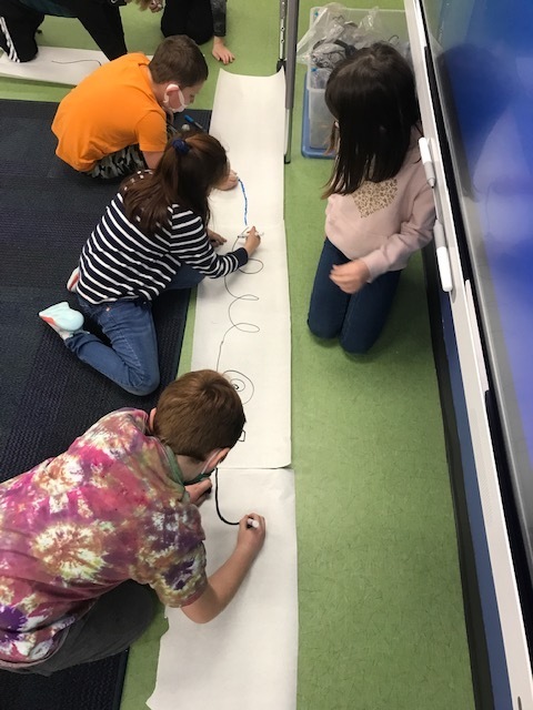 students drawing paths on paper for ozobots