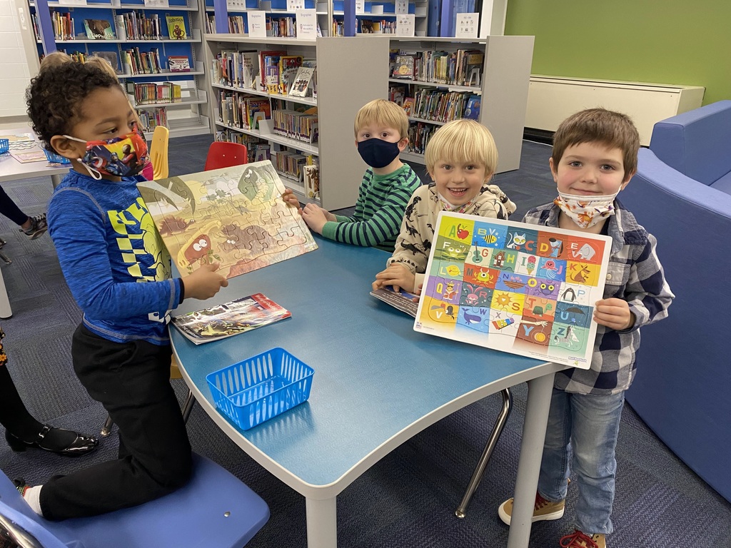 boys holding up completed puzzles in a library