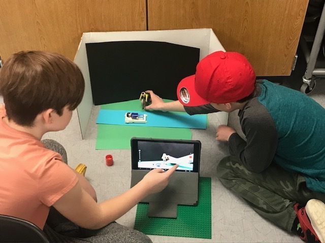 two students making a stop motion video with ipad