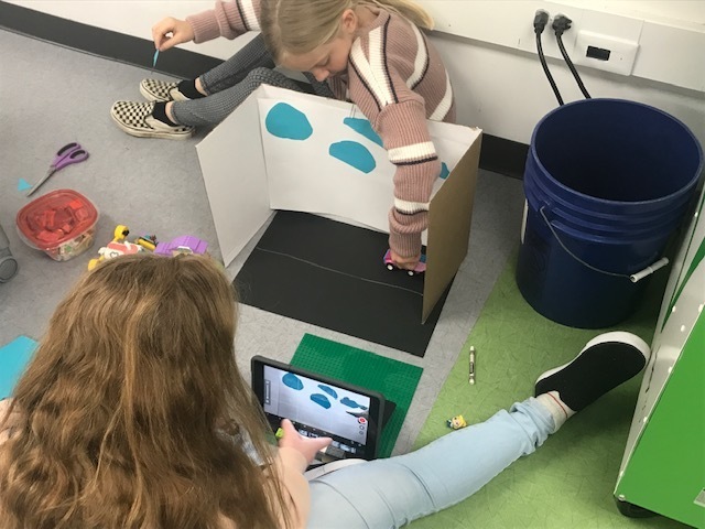 two students making a stop motion video with ipad