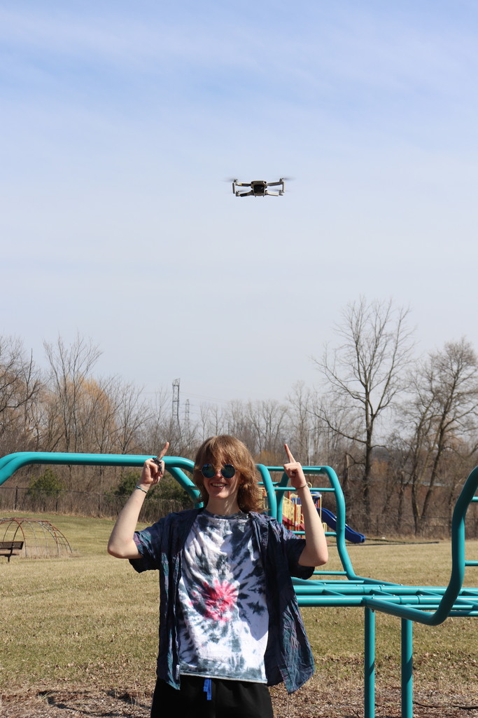 student  pointing at drone above
