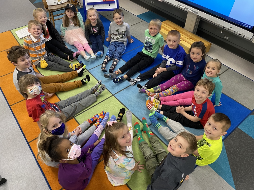 Students sitting on the floor showing their crazy socks.