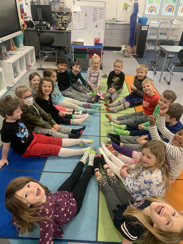 Students sitting on the floor showing their crazy socks.