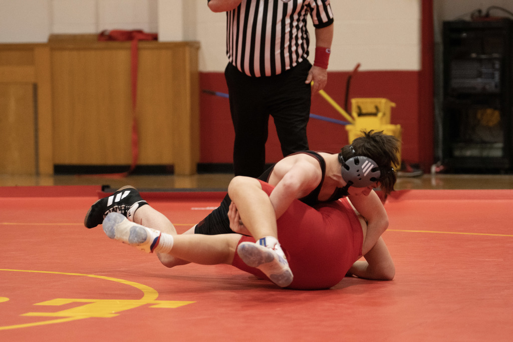 One wrestler turns another to pin him on mat