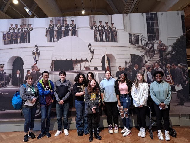 students in front of mural at museum