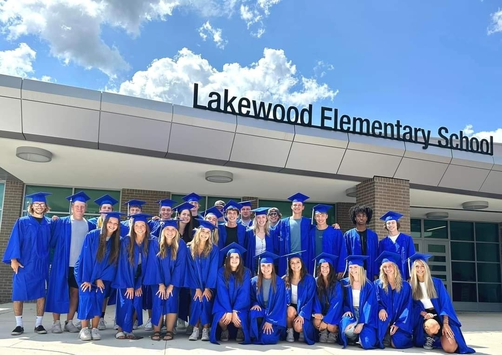 People in blue graduation gear standing in front of Lakewood Elementary School 