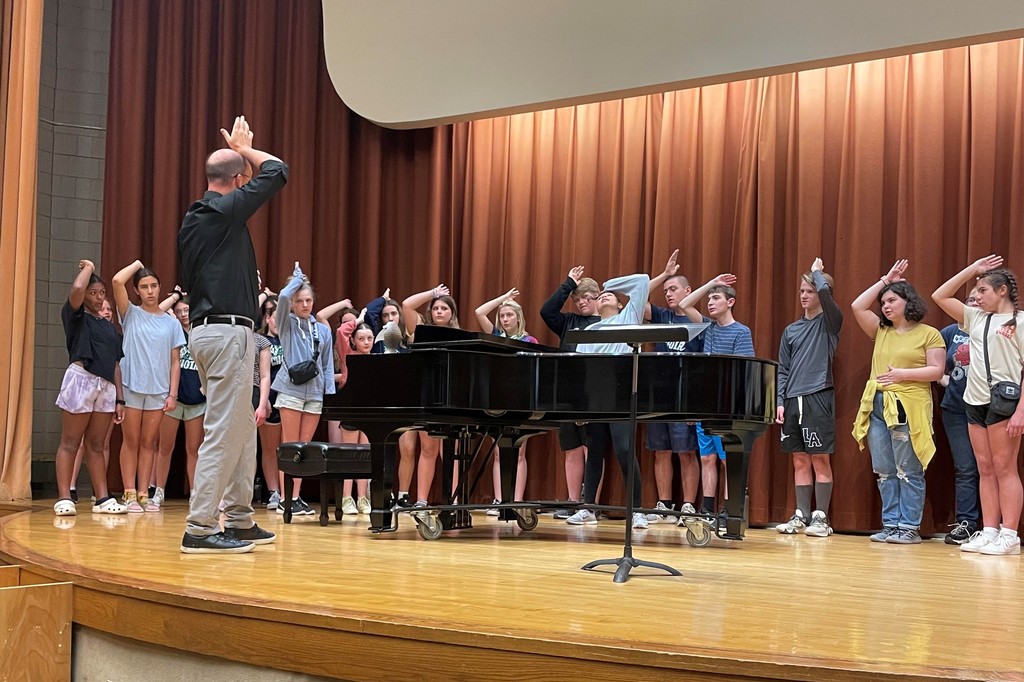 choir makes a sign with EMU professor