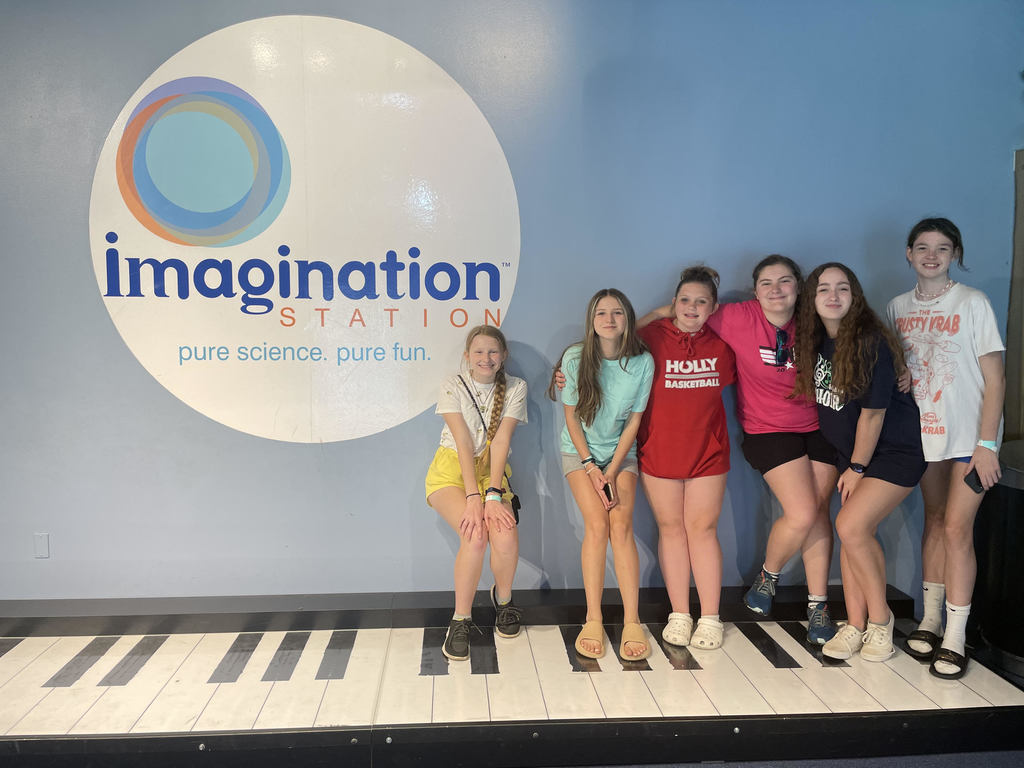 girls pose by Imagination sign