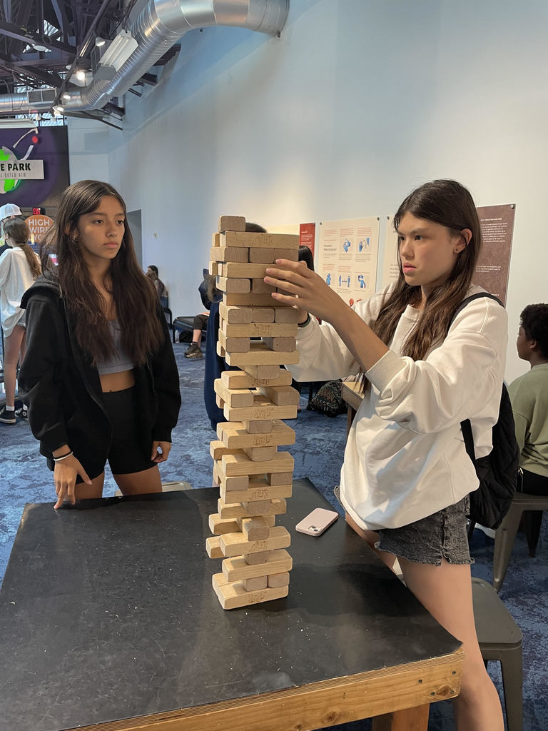 two girls stack wooden tower